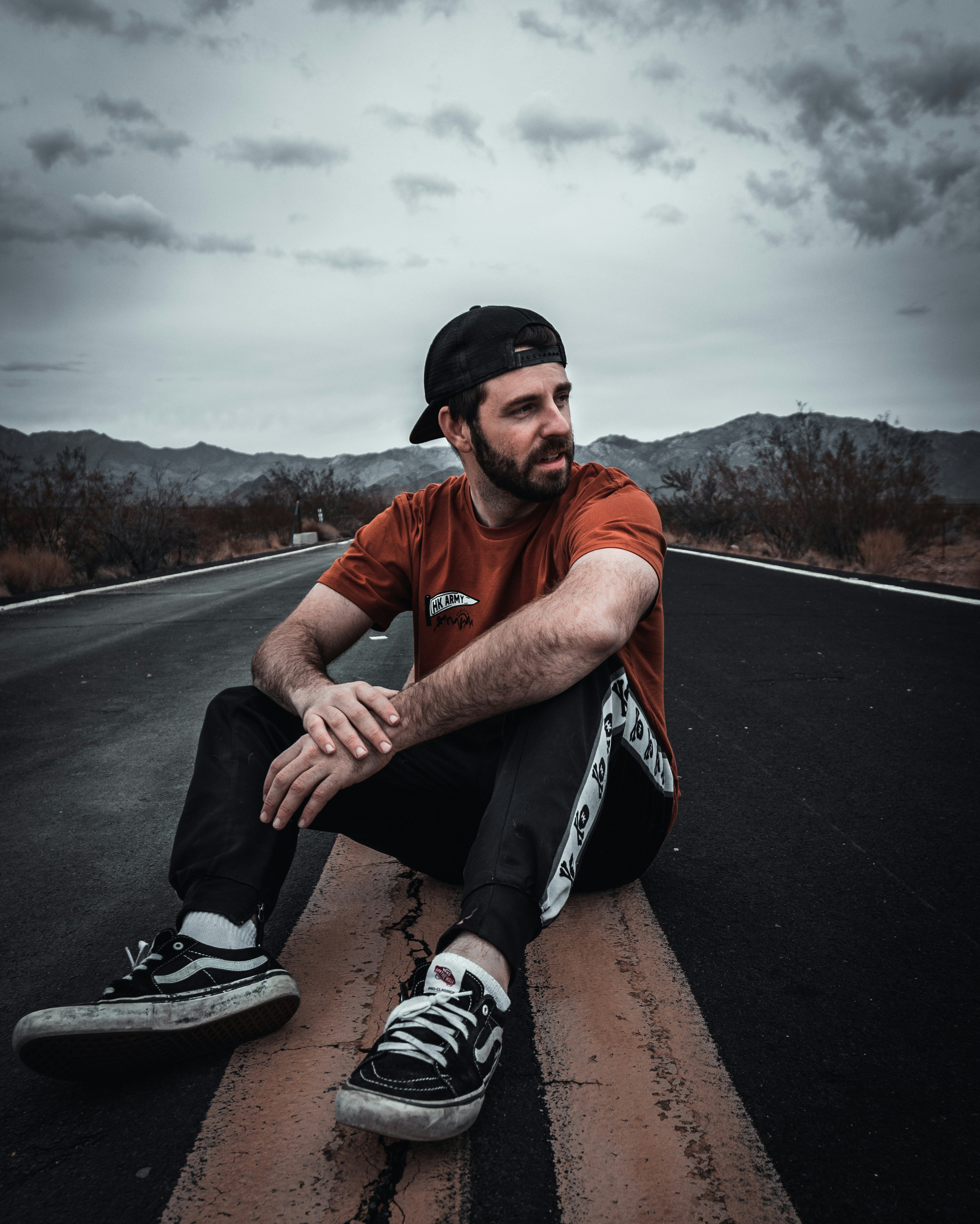 man in red crew neck t-shirt and black and white nike shoes sitting on black